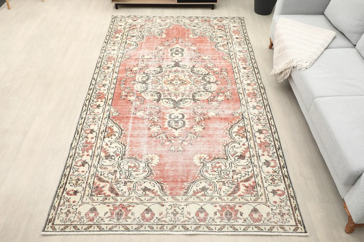 Overhead view of the rose and beige vintage Anatolian rug laid out in a room setting with a light-colored floor.