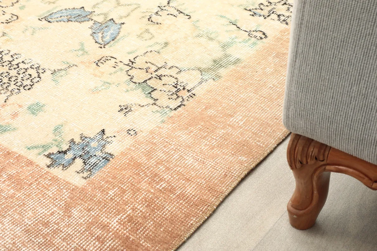 Corner of the rug in a room, showing its placement next to a piece of furniture
