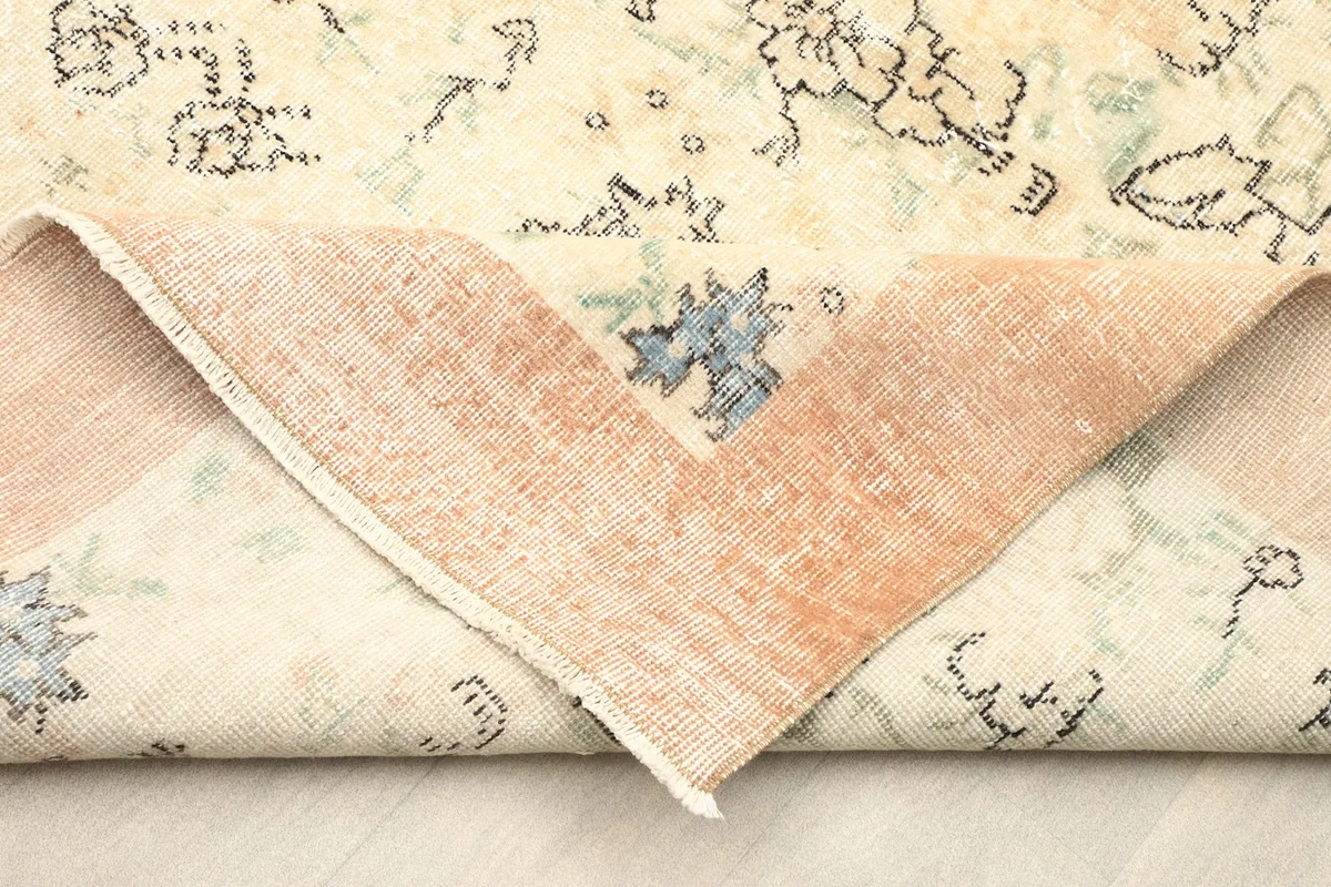 View of the rug's reverse side and pile, showing a folded corner with the rust border