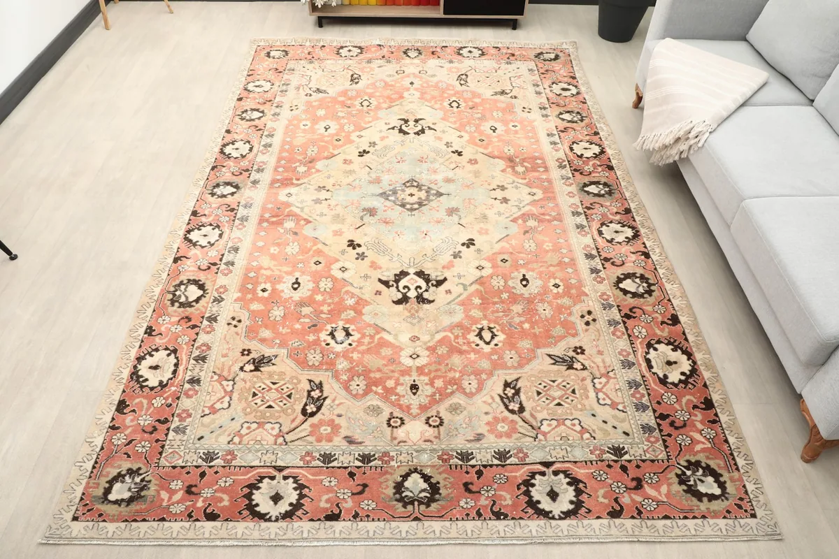 Large vintage rose area rug displayed in a living room setting with a light gray couch