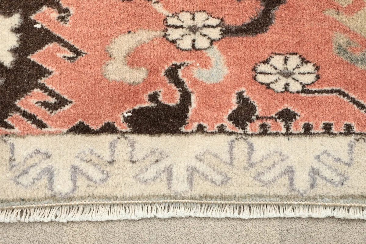 Close-up of the border pattern and fringe detail on the vintage rose rug