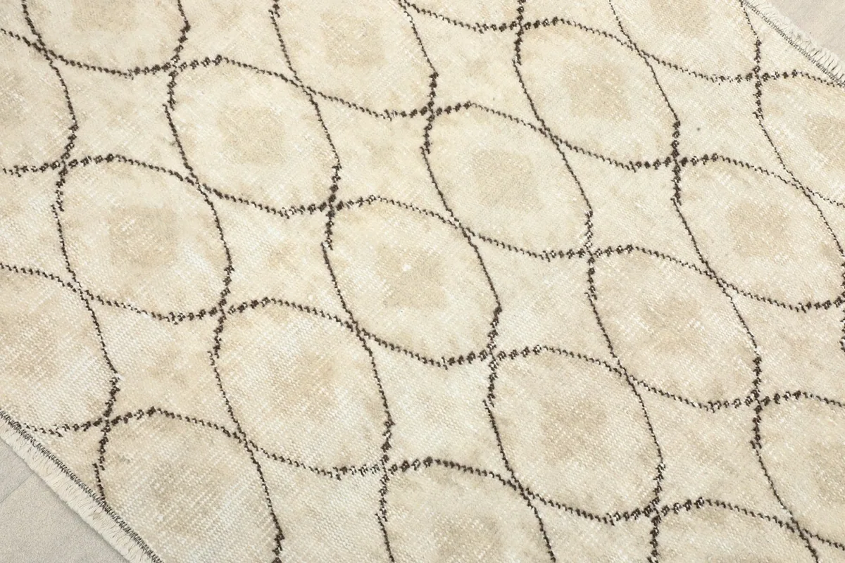 Close-up detail of the charcoal lattice pattern and ivory wool pile