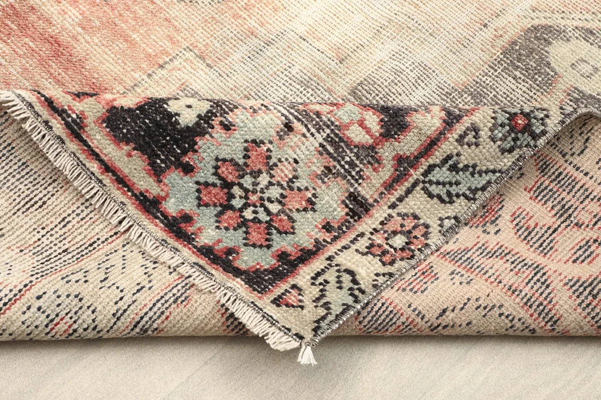 Folded corner of the rug revealing the tightly woven cotton foundation and reverse side