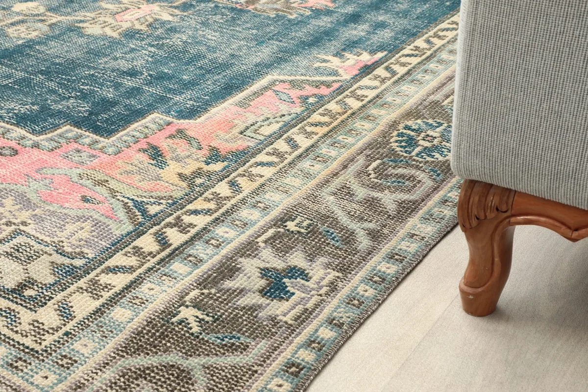 Partial view of the rug next to a sofa leg, showing border detail and room context.