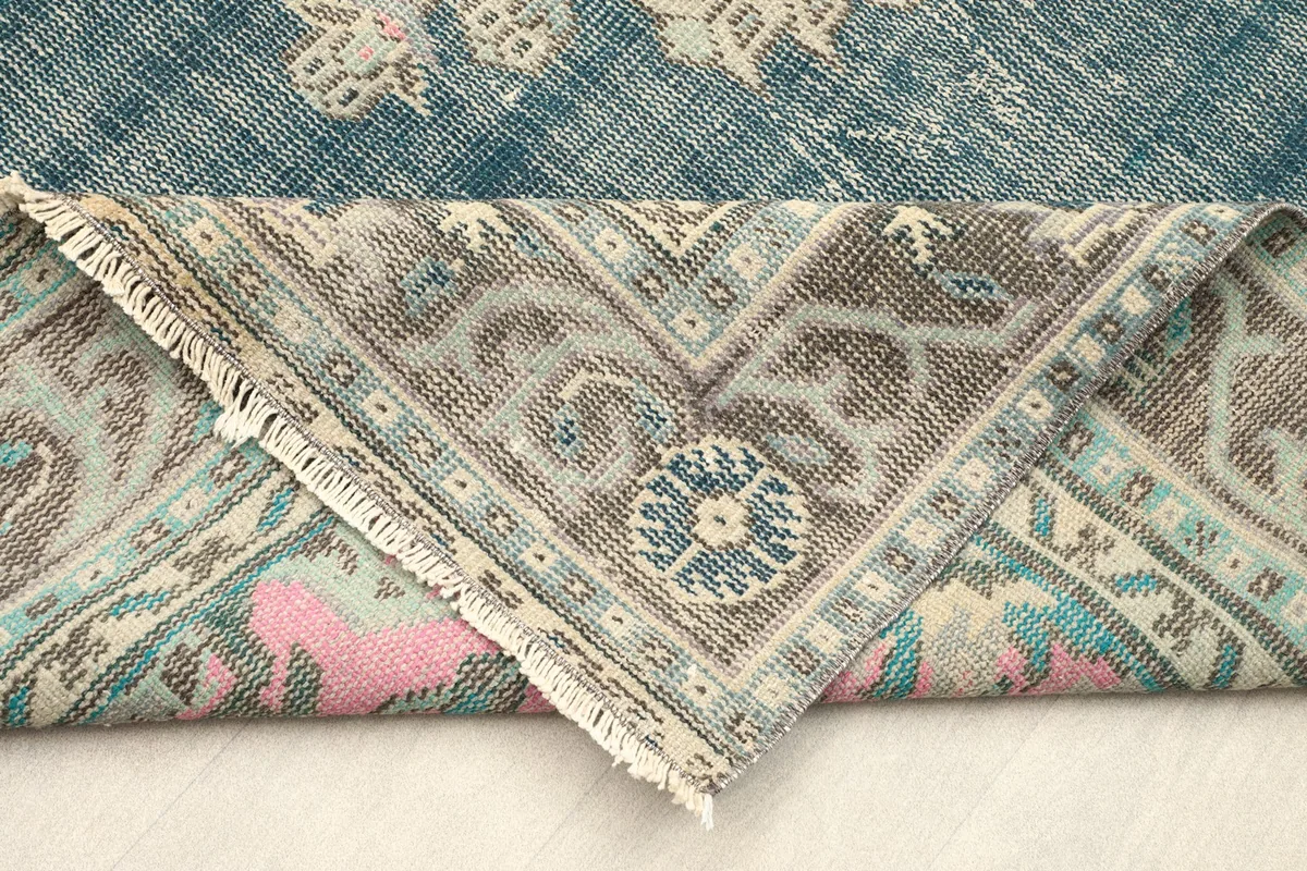 Folded corner of the rug revealing the backside of the hand-knotted construction and fringe.