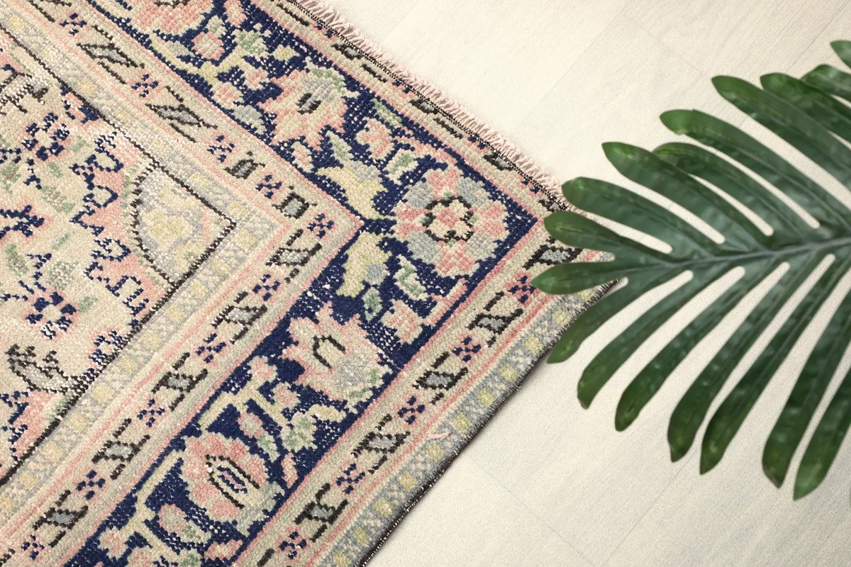 Corner detail of the rug's border and a decorative plant, emphasizing the craftsmanship