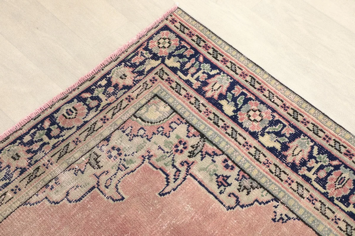 Corner detail showing the intricate floral patterns in the navy border against the rose field