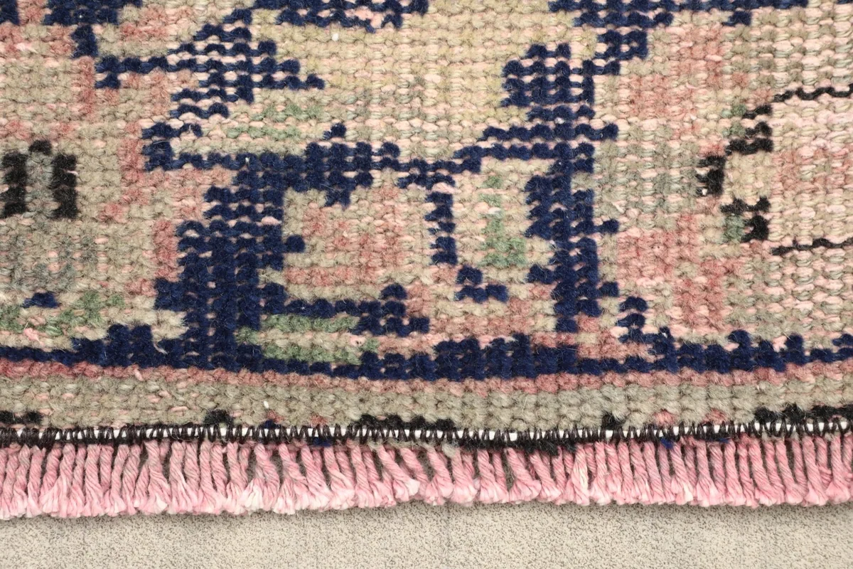 Close-up of the rug's fringe and a section of the navy and rose border detail
