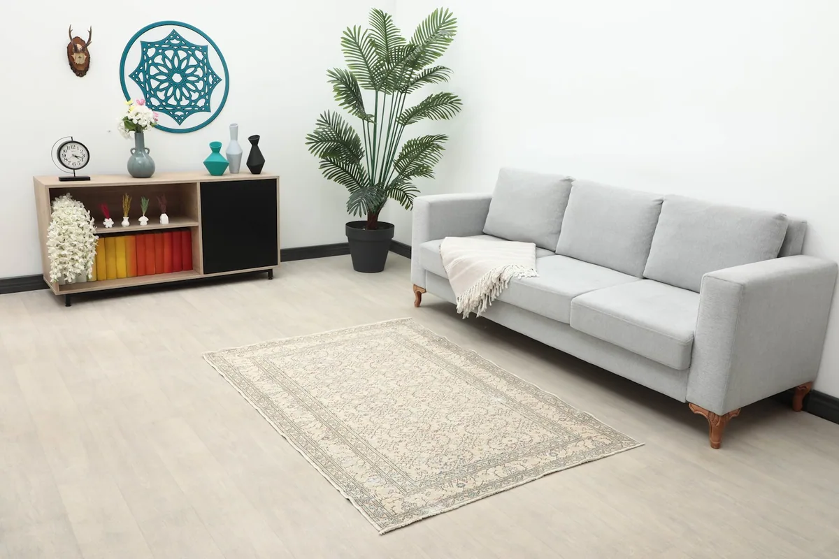 Ivory and gray floral rug decorating a living room space with a gray sofa and wooden cabinet
