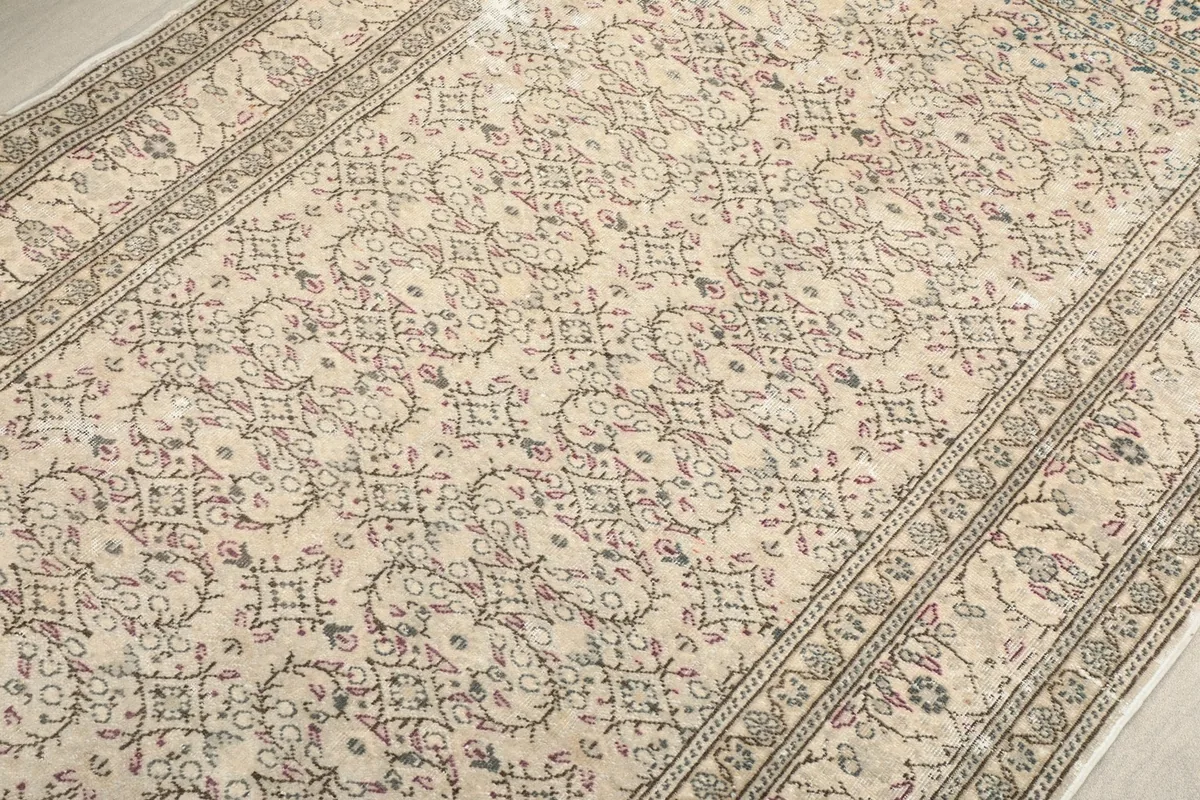 Close-up detail of the central ivory field with subtle gray and rose floral motifs