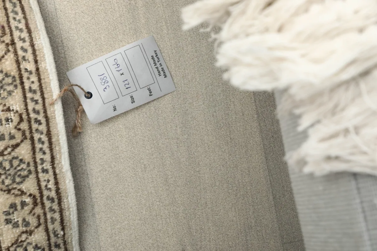 Product tag attached to the rug, showing details and origin, with fringe in the background