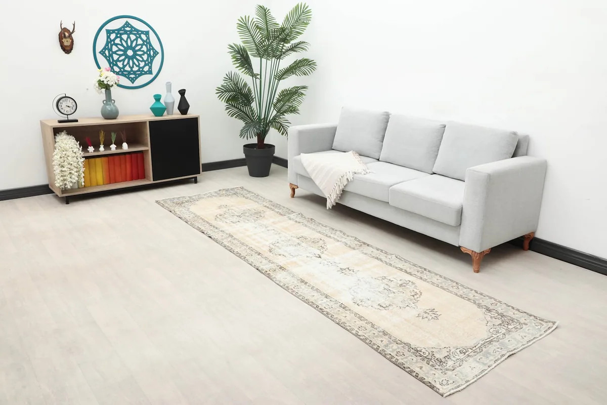 Wide shot of the runner rug in a living space with a sofa, plant, and cabinet, showing its scale.