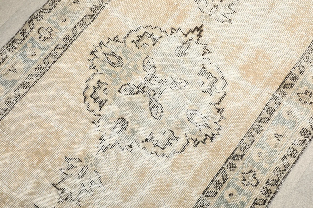 Detailed view of the distressed beige field and one of the gray medallion motifs.