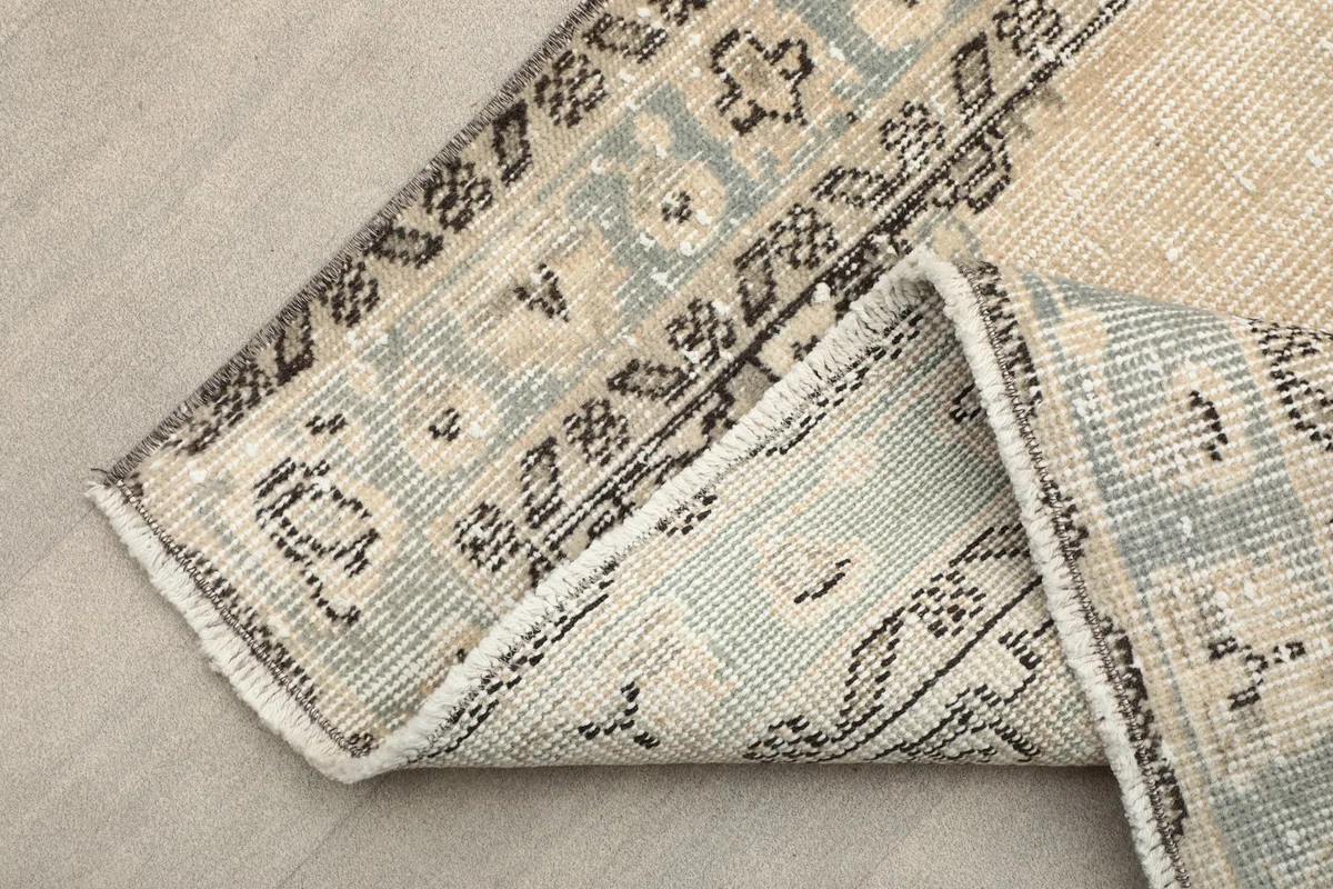 The rug folded to reveal the reverse side of the border and the cotton foundation.