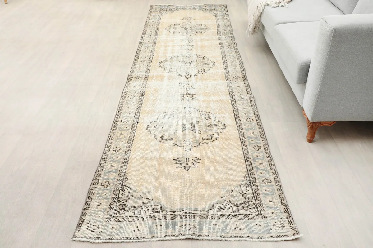 Overhead view of the beige and gray runner rug placed in a room next to a light gray sofa.