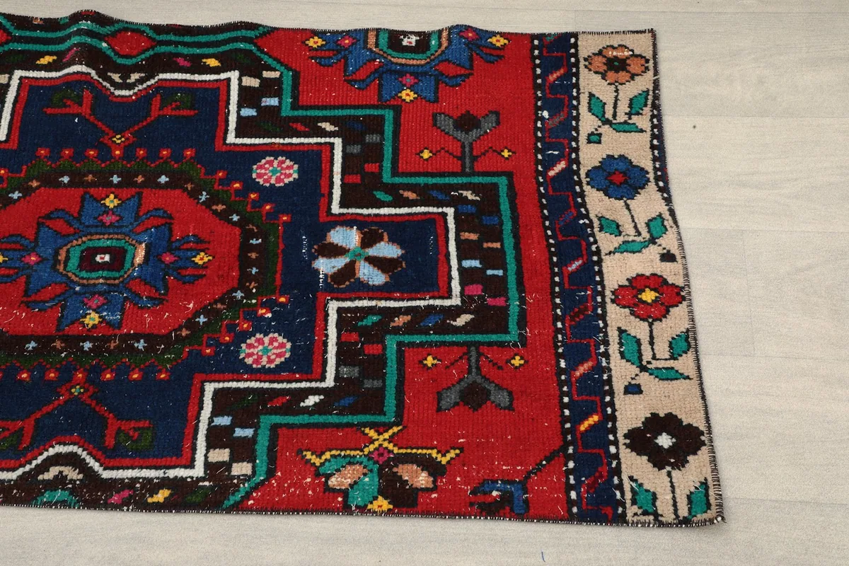 Close-up of the rug's border and main field, showing the intricate red, navy, and beige patterns.