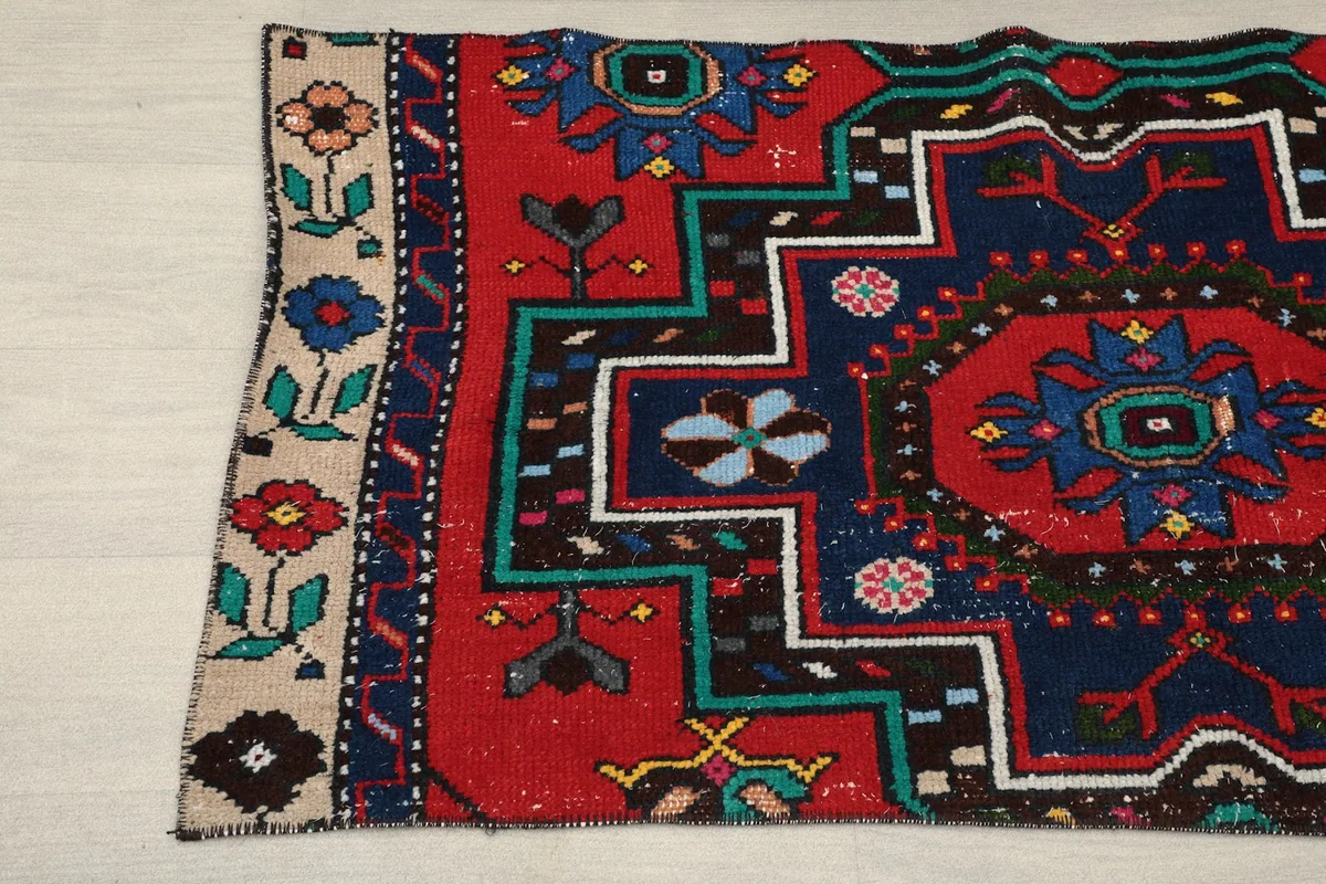 Detailed view of the rug's corner, displaying the beige border with floral motifs and geometric elements.