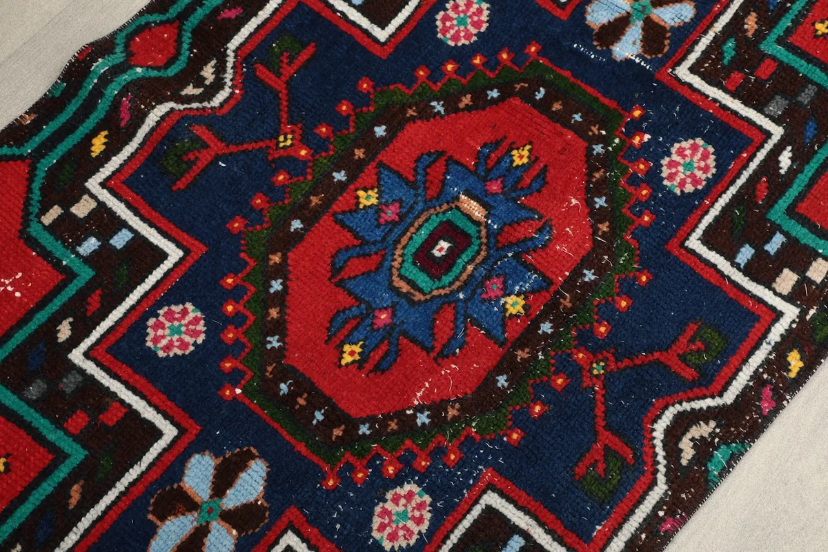 Close-up of the central medallion and surrounding geometric shapes in red, navy, and green tones.