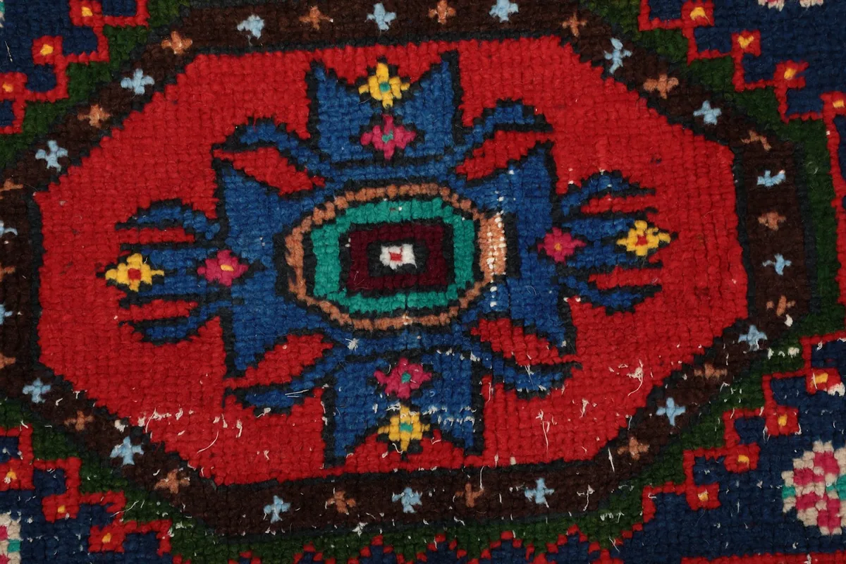 Extreme close-up showing the low wool pile and the texture of the hand-knotted vintage rug.