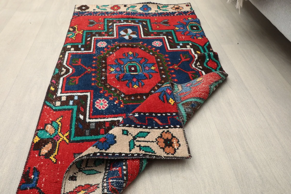 The vintage rug partially folded, showcasing the reverse side and the hand-knotted construction.