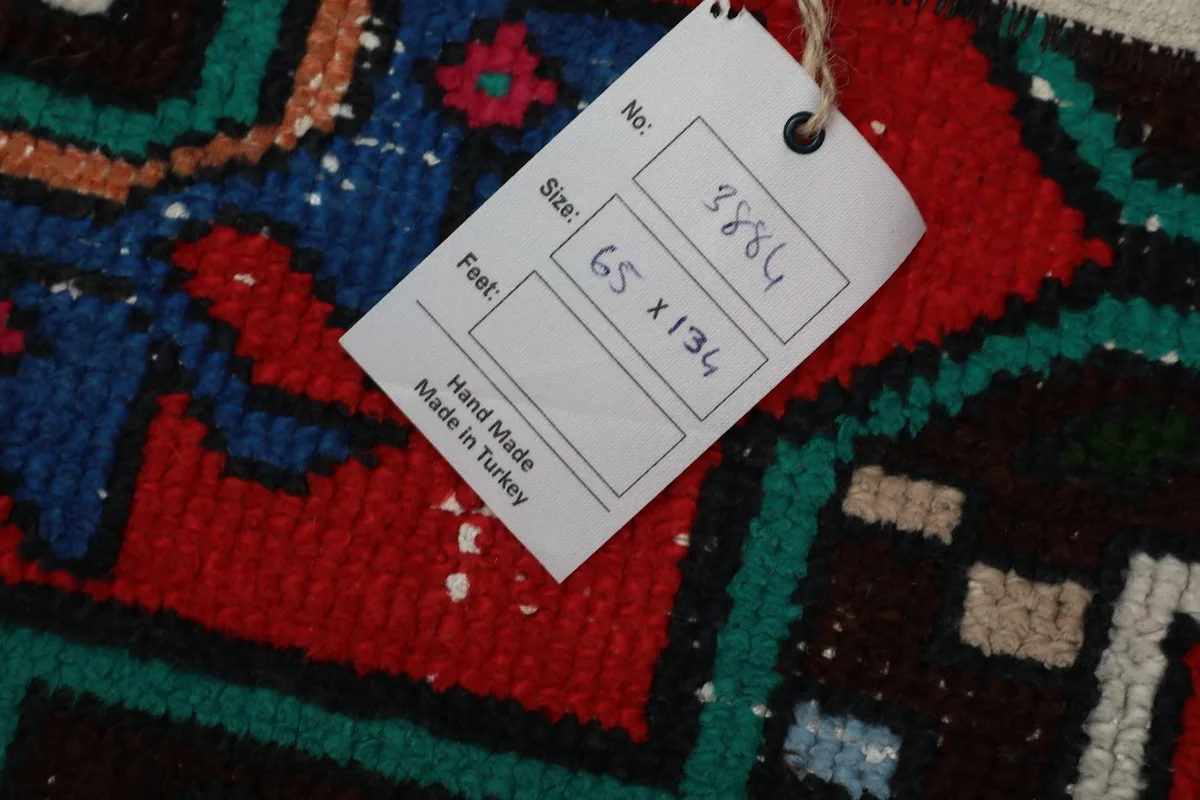 Tag displaying the rug's dimensions in centimeters and 'Hand Made Made in Turkey' on the rug's surface.