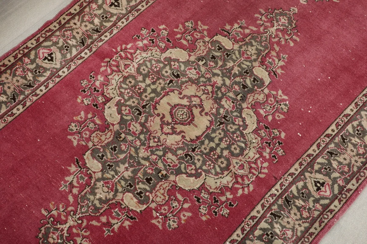 Overhead detail of the central medallion and surrounding floral elements in rose, beige, and gray