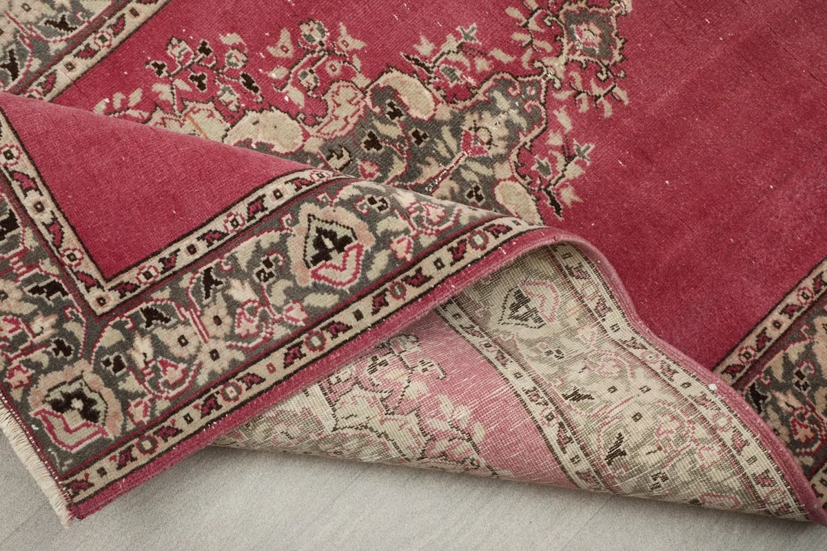 Angled view of the rug partially folded, highlighting the back and the main field color