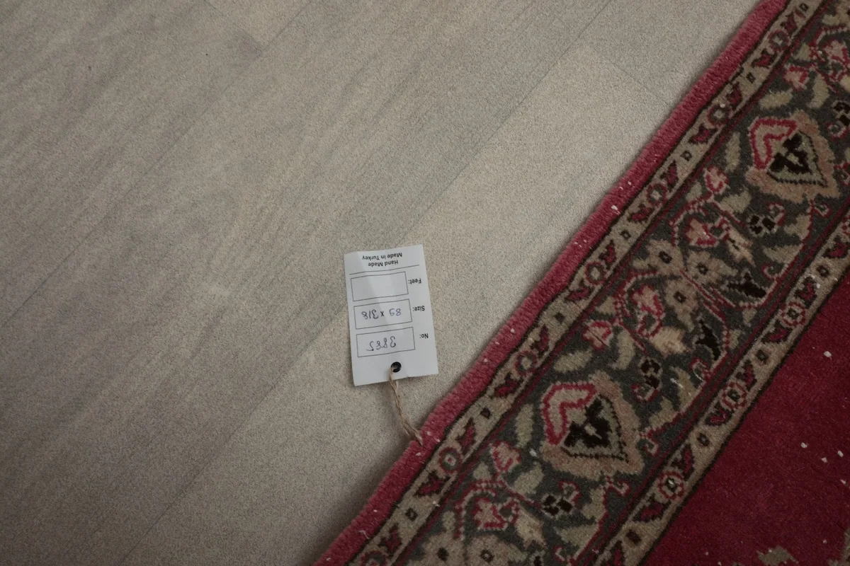 Corner of the rug with a product tag, showing the border design and part of the main field