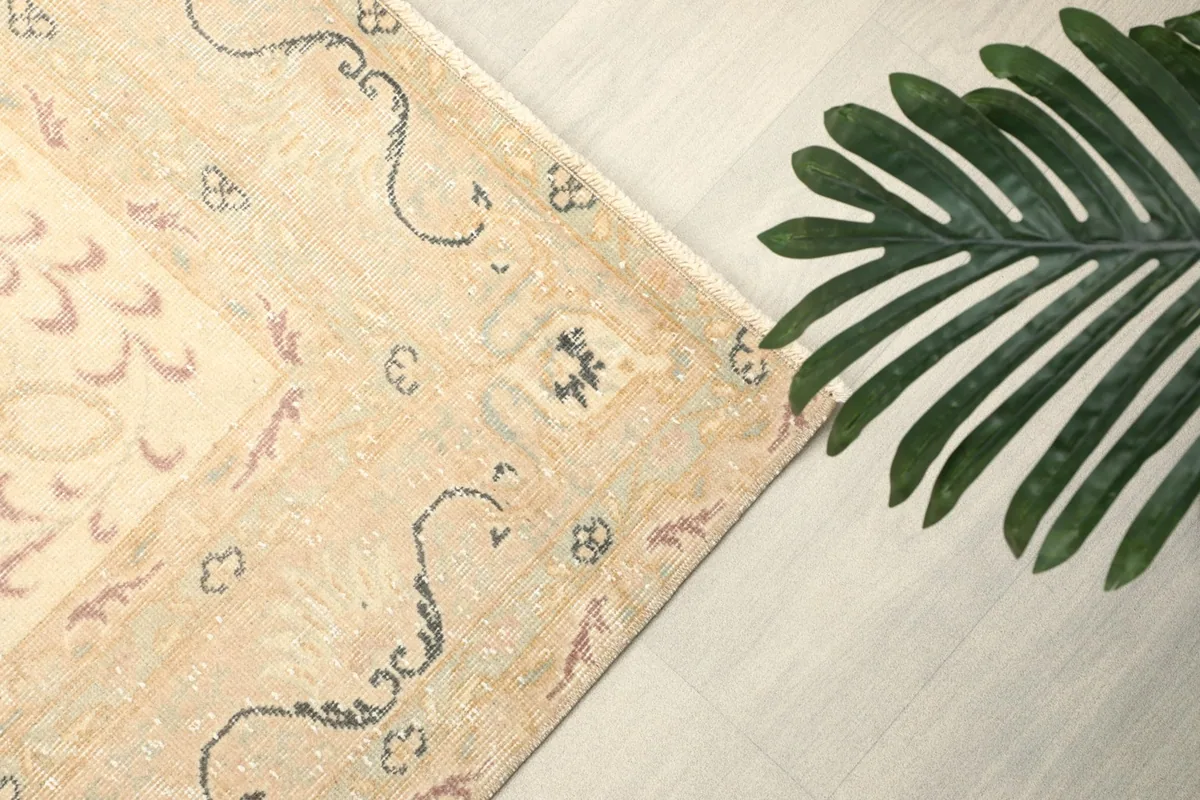 Detail of the rug's corner motif and a plant, showing the intricate design and color depth.
