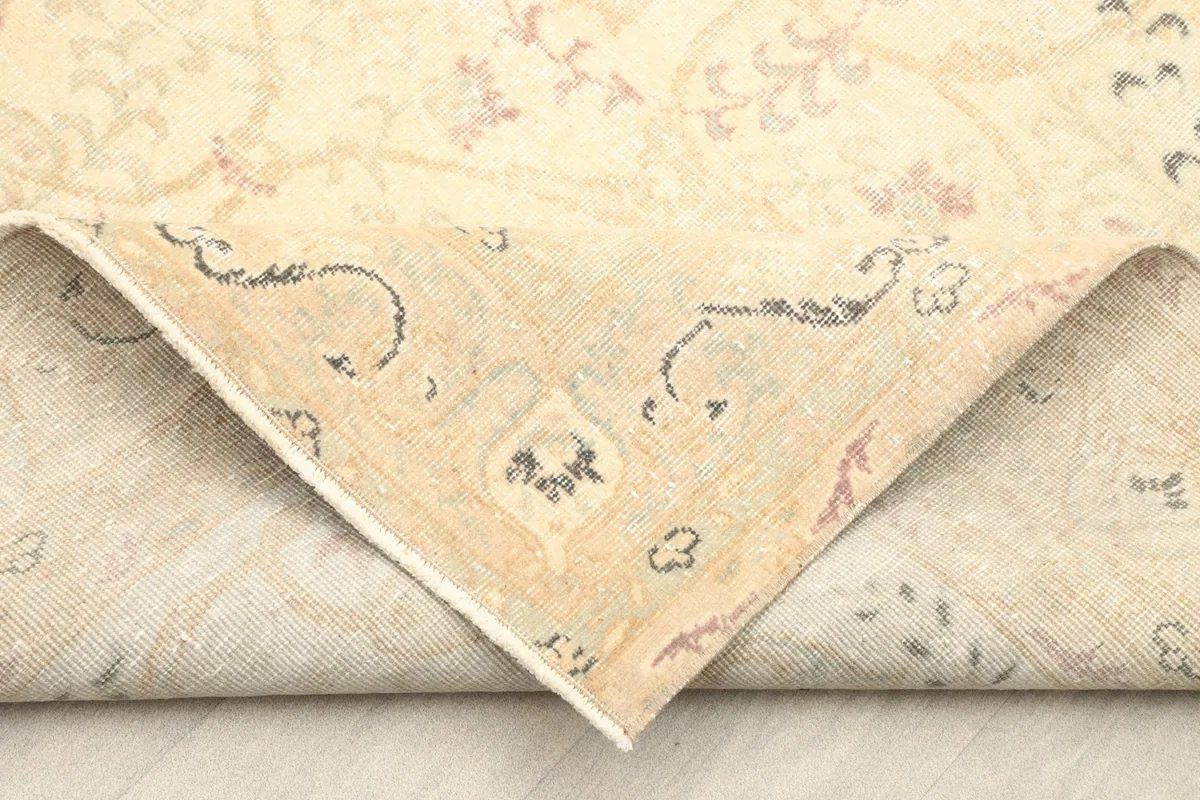 Corner of the rug folded back, showing the cotton foundation and craftsmanship of the hand-knotted piece.