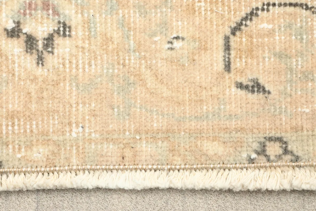 Close-up of the rug's fringe and edge, showing the hand-knotted wool pile and cotton foundation.
