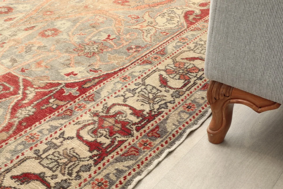 Detail view of the rug's border next to the leg of a gray sofa in a room setting
