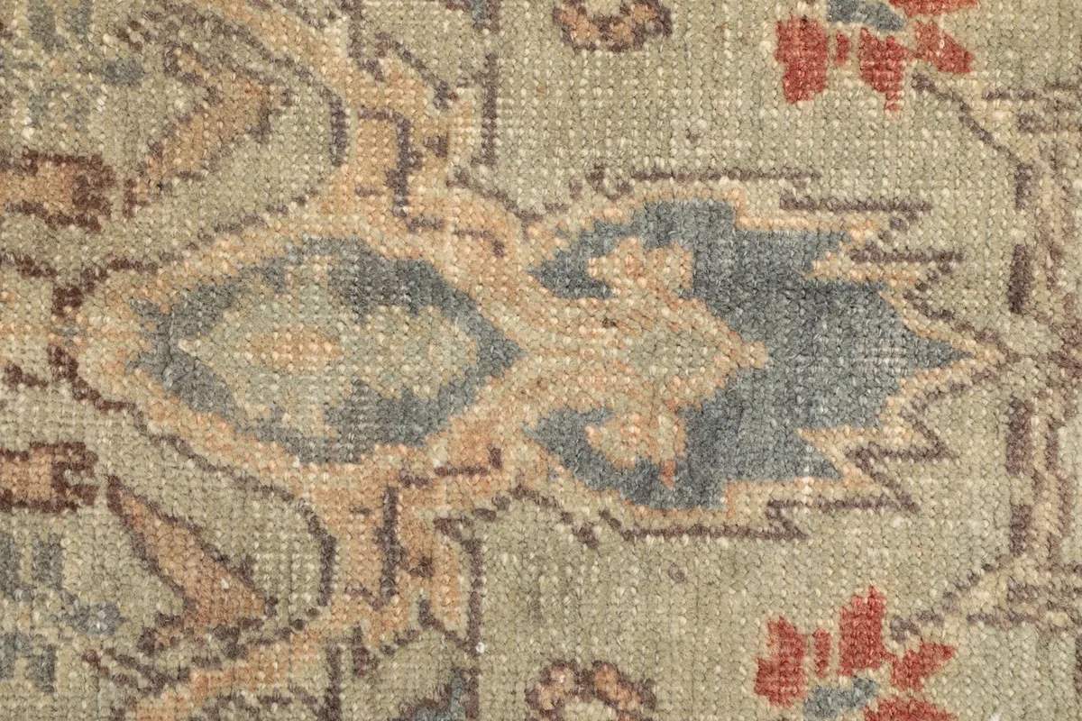 Close-up showing the low pile texture and color variations of the hand-knotted wool rug