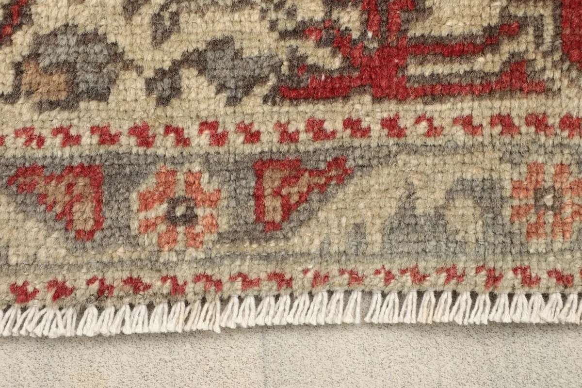 Close-up detail of the short white fringe and the border pattern of the hand-knotted wool rug
