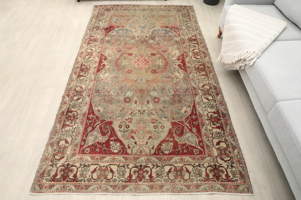 Overhead view of the gray and red vintage rug placed on a light floor next to a gray sofa
