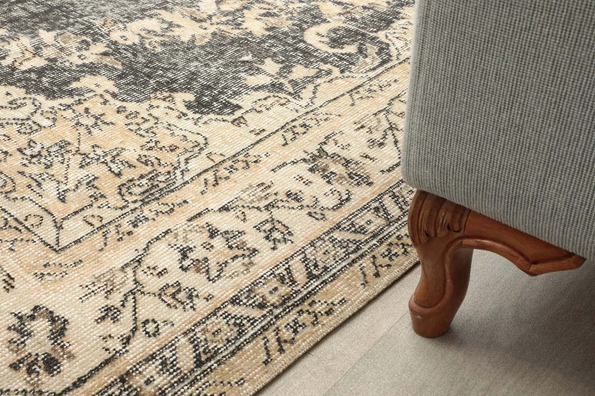Close-up of the rug's border and a furniture leg, highlighting the texture and patina