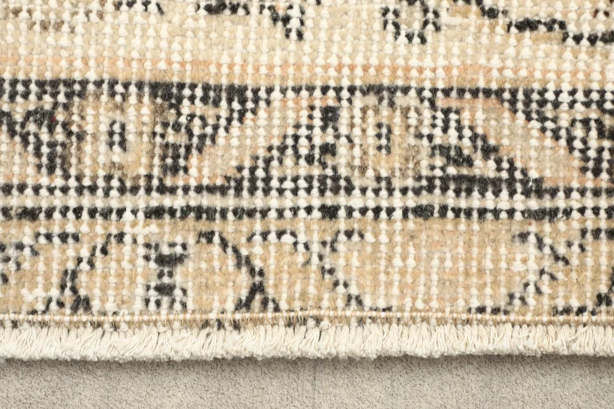 Close-up of the rug's outer border with black and beige geometric patterns