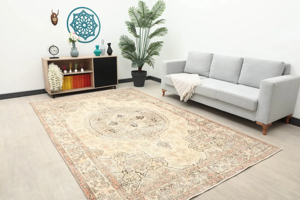 Ivory and rose Anatolian rug displayed in a room with a sofa and side cabinet