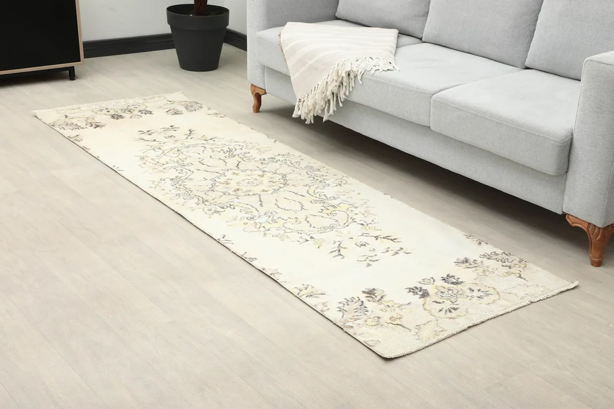 Runner rug showing its full length on a light floor, beside a sofa
