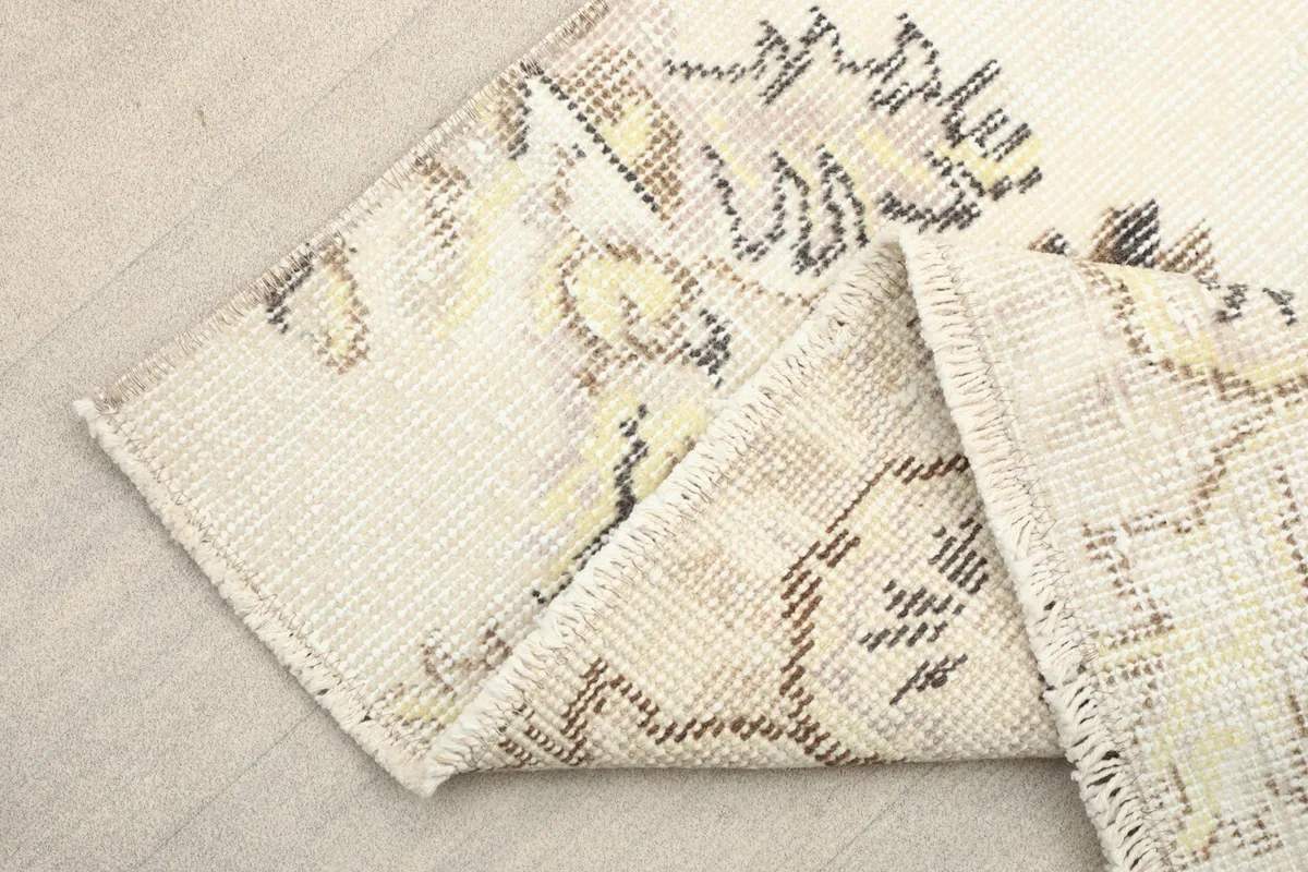 Folded corner of the rug, revealing the dense wool pile and cotton foundation