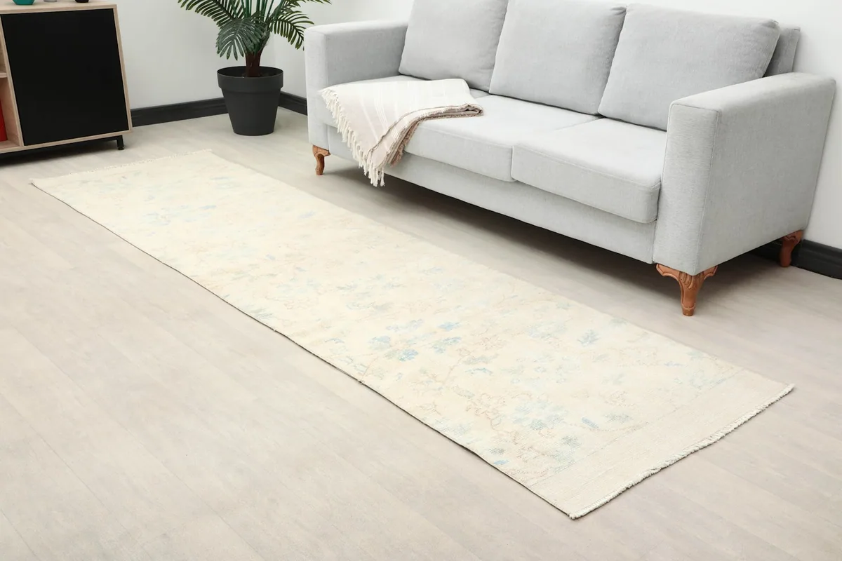 Room view showing the full length of the cream runner rug with subtle blue and rust floral patterns.