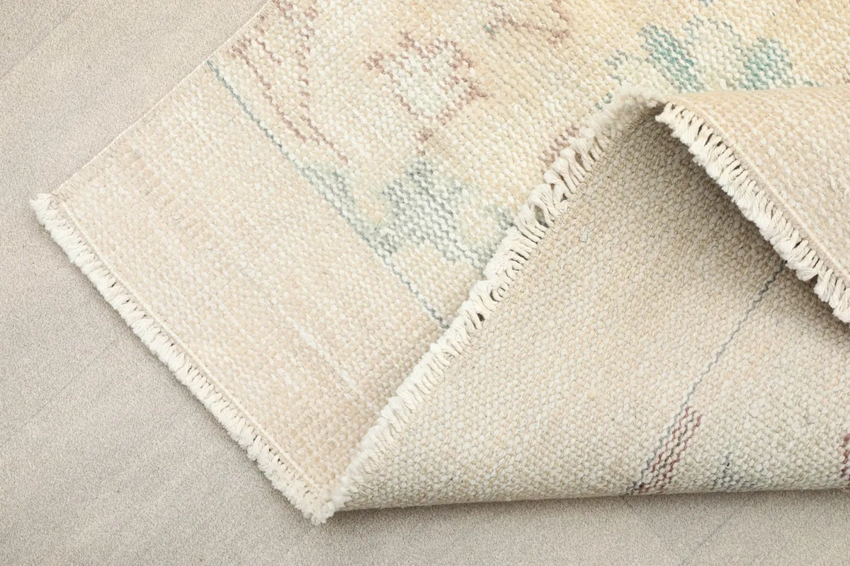 Corner of the rug folded to show the cotton foundation and the reverse side of the hand-knotted construction.