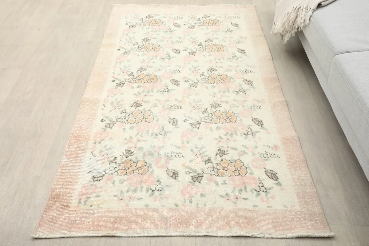 An ivory floral area rug placed in a living room setting, viewed from an elevated angle.
