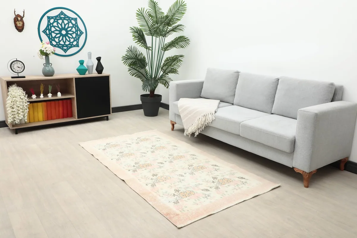 Longer view of the ivory rose rug in a room with a sofa and side cabinet, showing its scale.