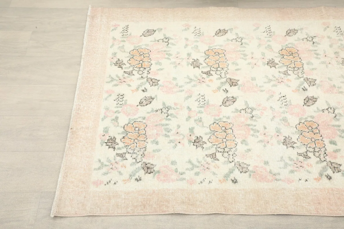Another close-up of a rug corner, showing the faded colors and gentle wear on the border.