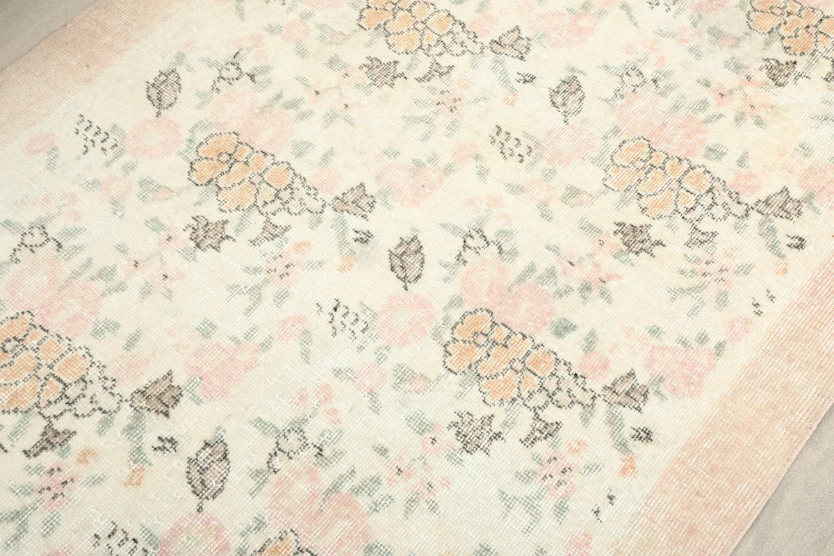 Detailed view of the rug's surface, focusing on the rose, orange, and green floral patterns.