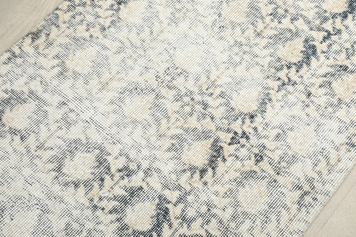Detailed view of the wool pile and the intricate, faded motifs of the vintage rug.