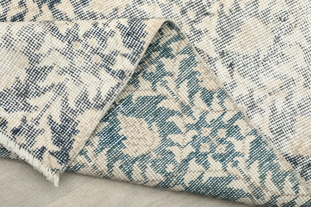 Angled view of the rug's underside, showcasing the hand-knotted construction and fringe.