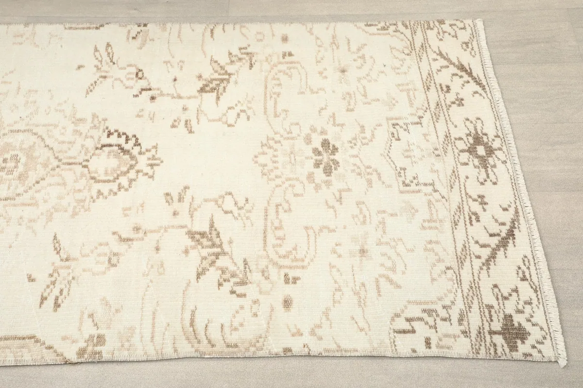 Close-up of the runner rug's end, showing tan geometric motifs and border