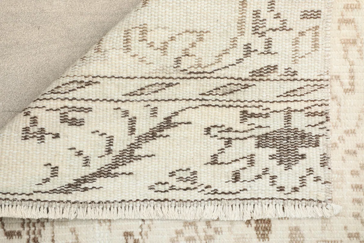 Corner of the runner rug folded to show the cotton foundation and fringe